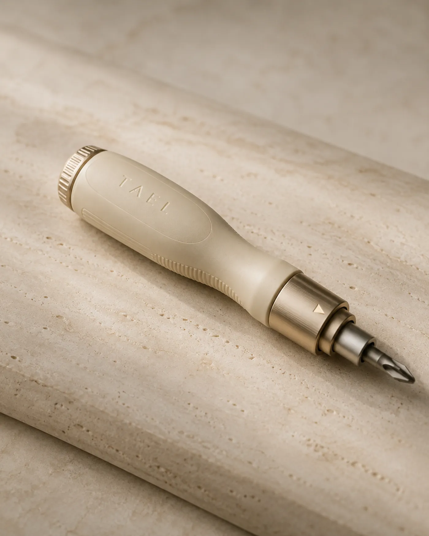 The Tael ratcheting screwdriver resting on warm travertine stone.
